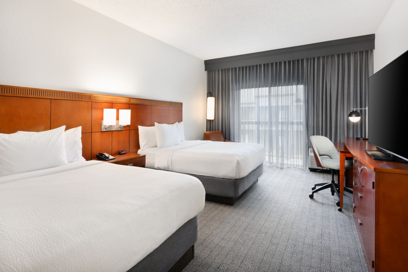 Queen/Queen guest room with two beds, desk, and TV